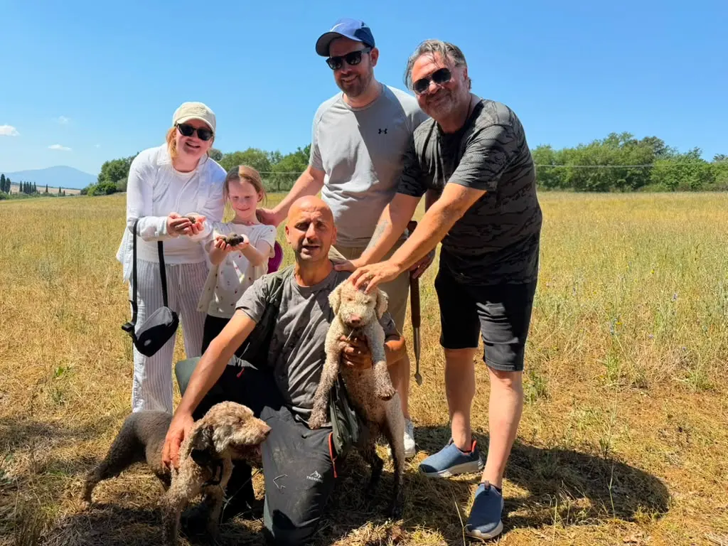 Guests with a local truffle hunter and trained dogs during a private truffle hunt in Val d'Orcia